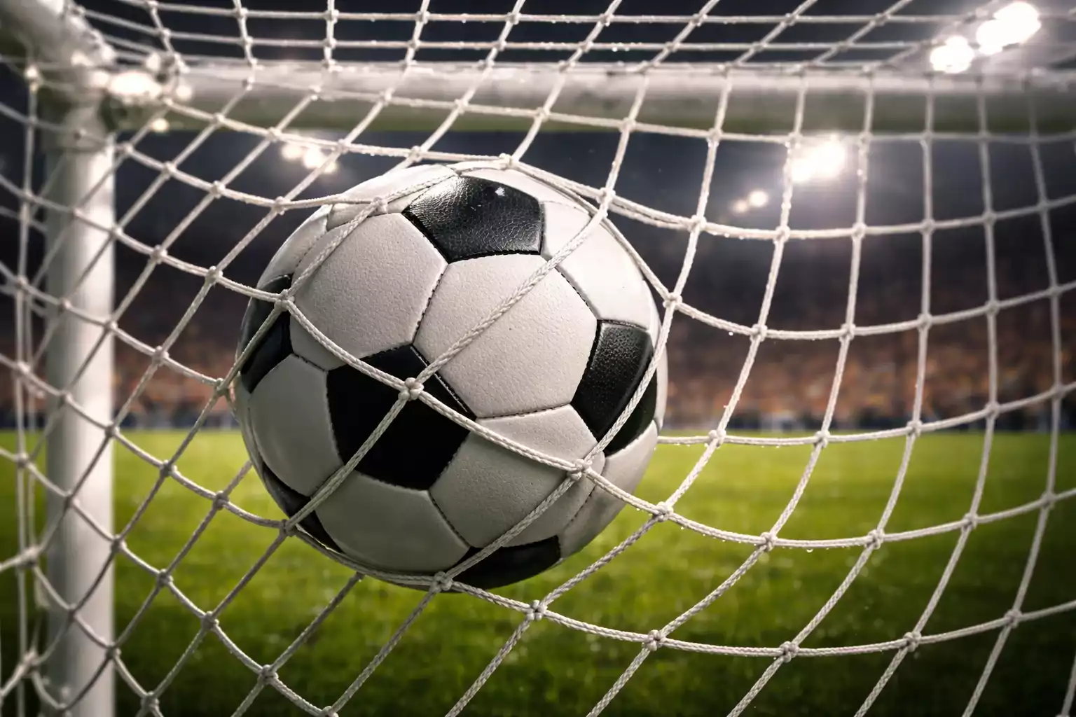 Red de una portería de fútbol vista desde dentro tras encajar un gol en un estadio lleno